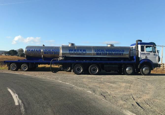 Tapped out water truck and tanker parked infront of dry rural landscape