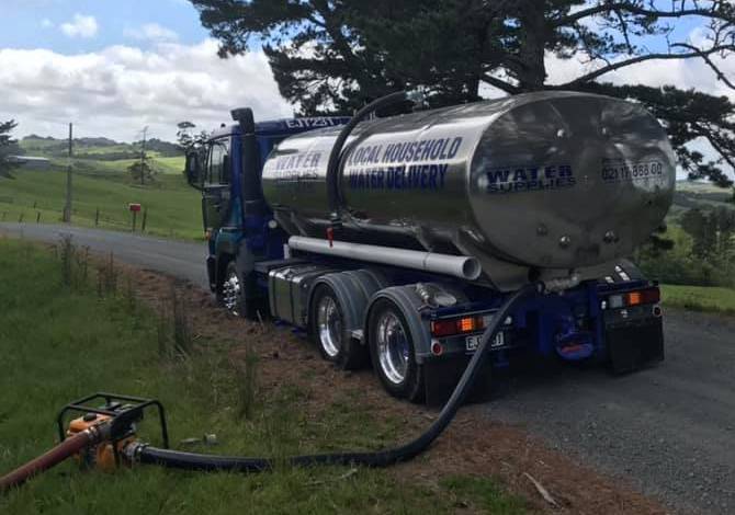 Tapped Out truck parked on rural road pumping water